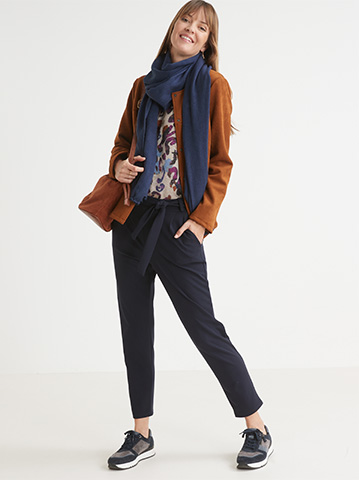 Look ville avec le tee-shirt en maille lurex, son pantalon élastiqué bleu grande taille femme et sa veste courte camel. 